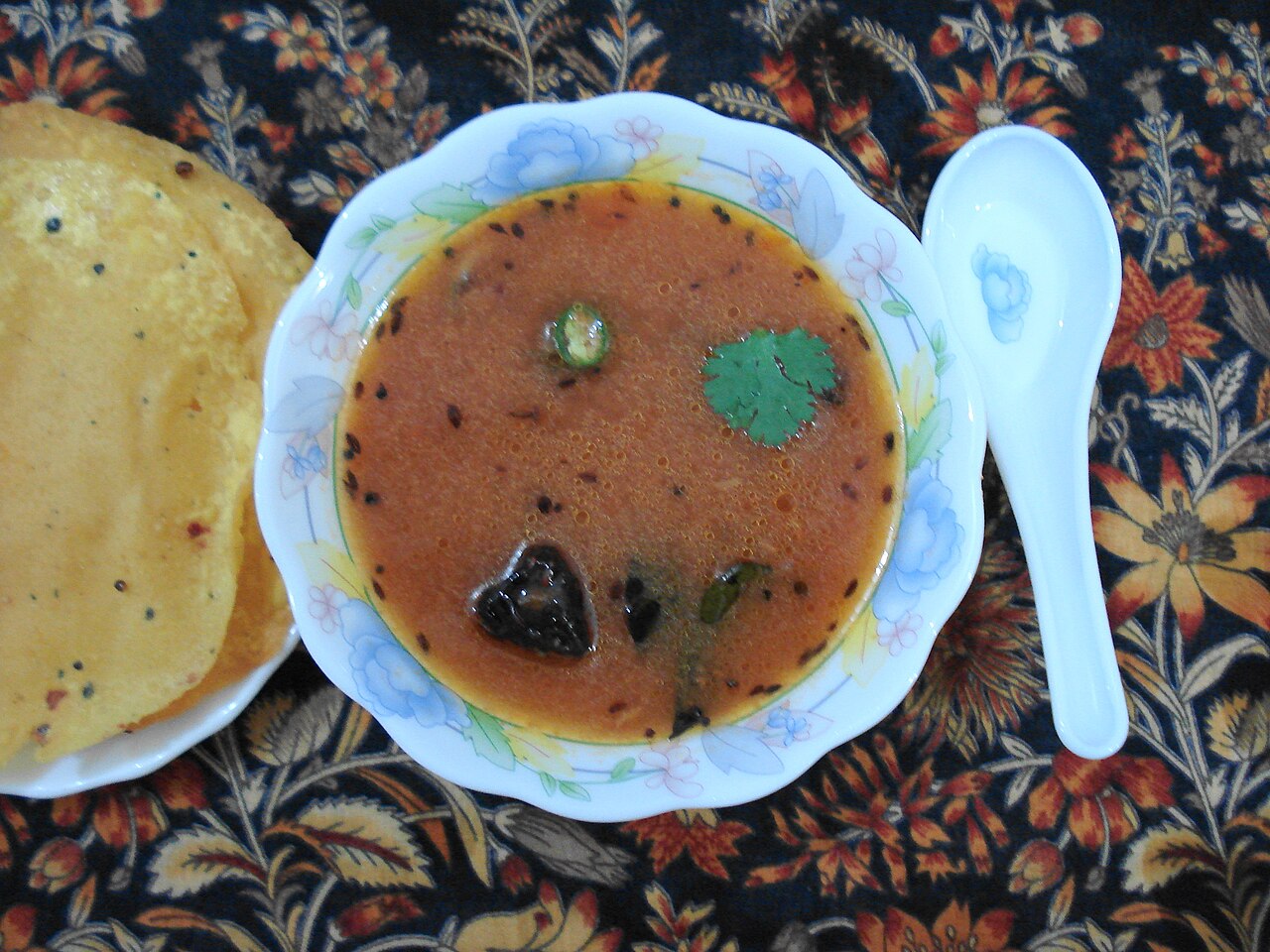 A bowl of rasam served with papad